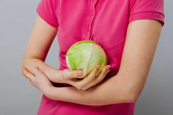 生の食品、野菜コンセプト。灰色の背景の上の手に赤キャベツを持ったカジュアルな服の良い探している女の子が笑顔の肖像画。健康的な肌、光沢のある茶色の髪。クローズ アップ。スタジオ撮影. — ストック写真