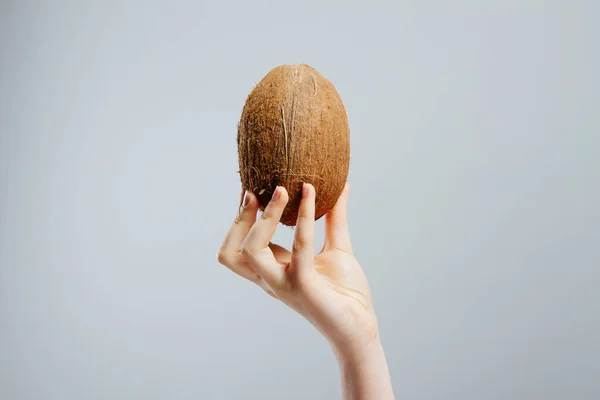 Kvinna med mutter kokos i handen mot grå bakgrund — Stockfoto