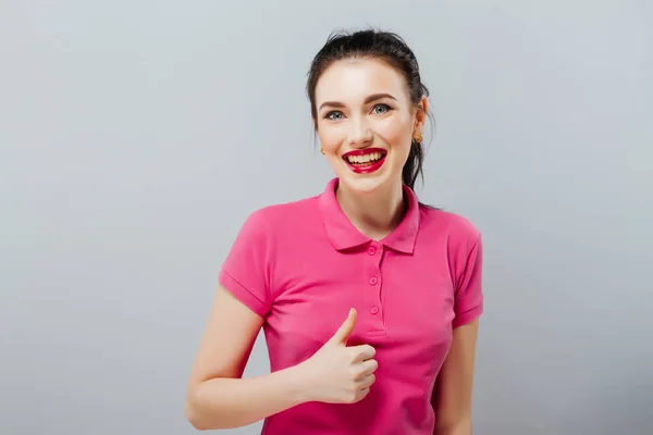 Sorridente bella giovane donna in rosa mini abito mostrando pollice in su e ammiccando — Foto Stock