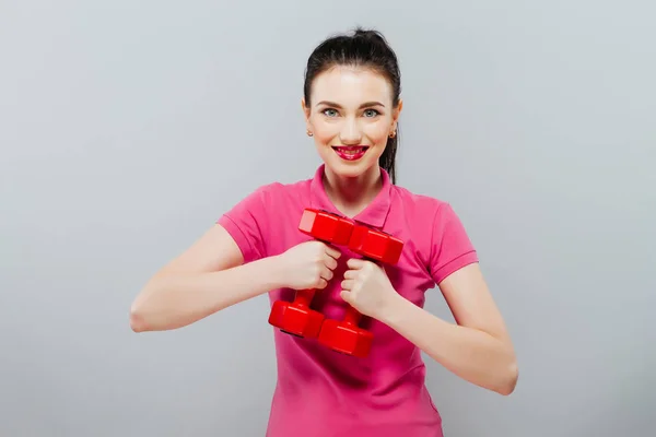 Una ragazza con due manubri di plastica in mano. Fondo grigio . — Foto Stock