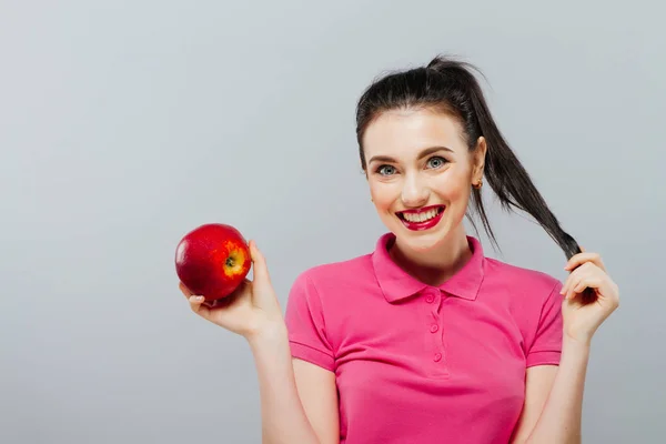 Retrato de una guapa morena con una manzana, fondo blanco — Foto de Stock