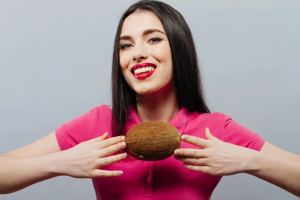 Красивая женщина с кокосом в руках на сером фоне — стоковое фото