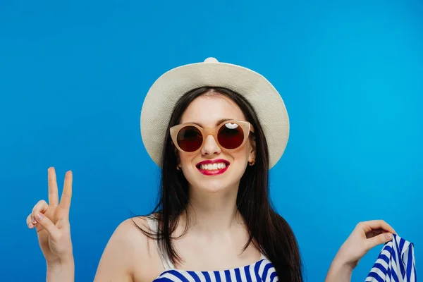 Brunette fille avec des lunettes de soleil et chapeau sur fond bleu — Photo