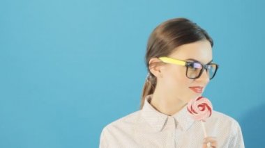 Lolipop inanılmaz güzel seksi kadın mavi zemin üzerine. Stüdyo bir lolipop tutan bir esmer kız portresi. Makyaj