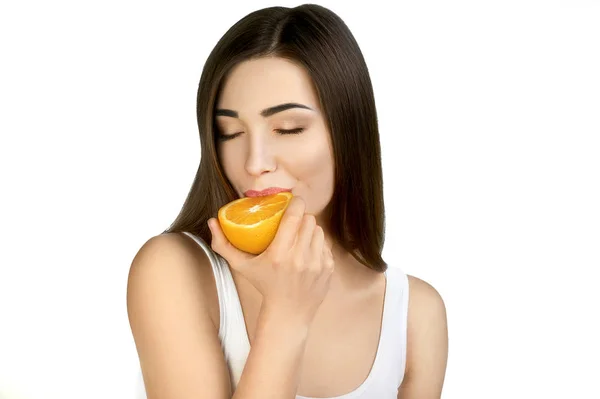 Retrato de niña alegre comiendo naranja jugosa sobre fondo blanco . — Foto de Stock