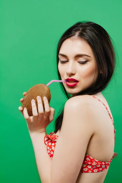 Sensual Brunette with Tropical Cocktail in Hands Posing on Green Background.