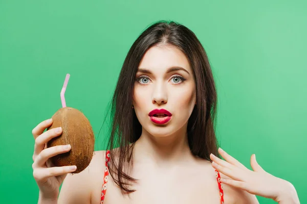 Sorprendida morena con cóctel tropical en las manos sobre fondo verde . — Foto de Stock