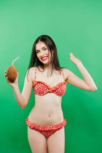 Retrato de chica despreocupada en traje de baño brillante posando con cóctel en el estudio sobre fondo verde . — Foto de Stock