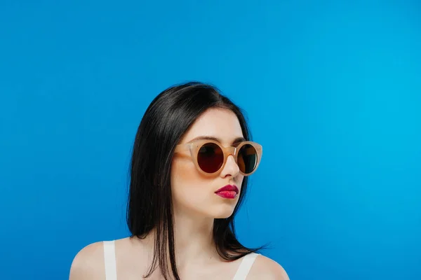 Vue latérale du visage féminin avec des lunettes de soleil propres et parfaites sur fond bleu . — Photo