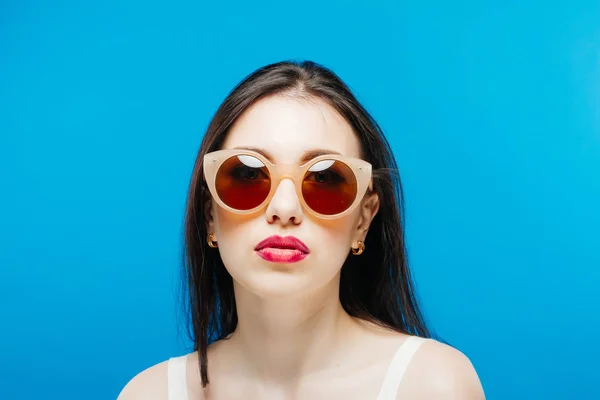 Visage féminin avec des lunettes de soleil propres et parfaites sur fond bleu . — Photo