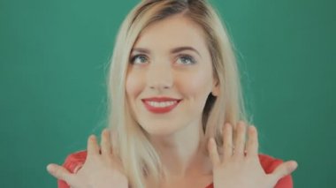 Closeup yeşil zemin üzerine geniş açılış gözlü sürpriz genç kadın portresi. Sarışın kız: Grimacing Studio.