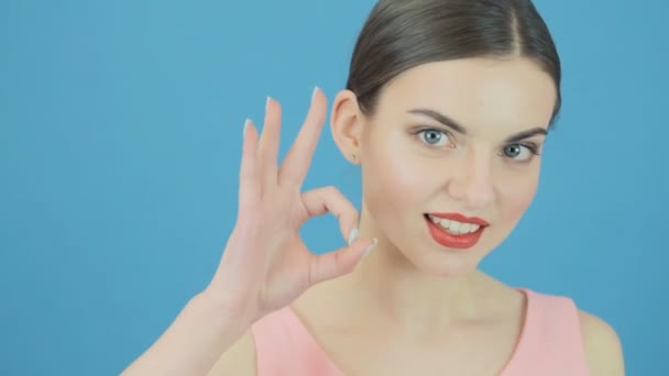 Cute Playful Woman is Showing Ok Sign on Blue Background in Studio. Beautiful Brunette Gesticulates Looking at the Camera. — Stock Video