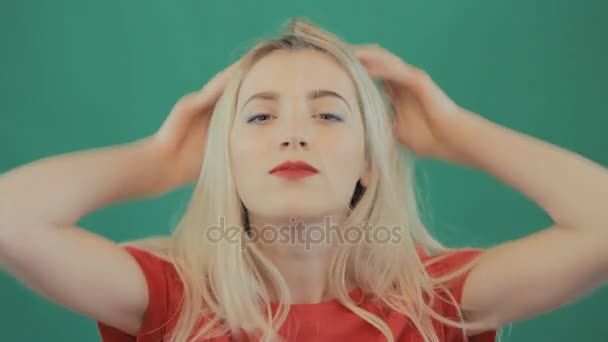 Ritratto di bella donna bionda arrabbiata su sfondo verde. Ragazza emotiva con capelli lunghi e labbra rosse sensuali in studio . — Video Stock