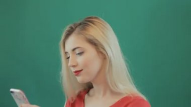 Genç kadın ile Studio yeşil zemin üzerine Smartphone şaşırttı. Mobile kullanan kadın portresi closeup.