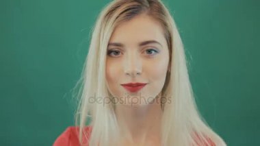 Uzun saçlı yeşil arka planda seyir yukarı ve aşağı şehvetli sarışın kız closeup portresi.