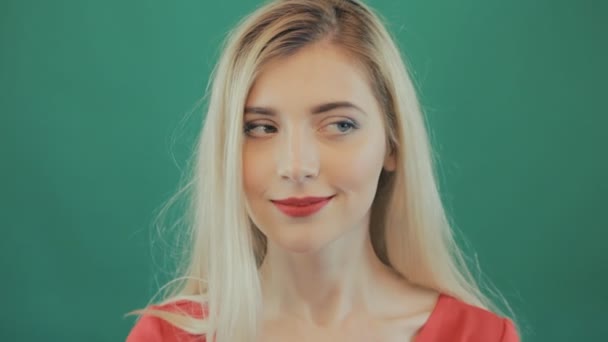 Koketní smyslná blondýnka s dlouhými vlasy, při pohledu vlevo a přímo na zelené pozadí. Portrét roztomilé mladé ženy šklebící se ve studiu. — Stock video