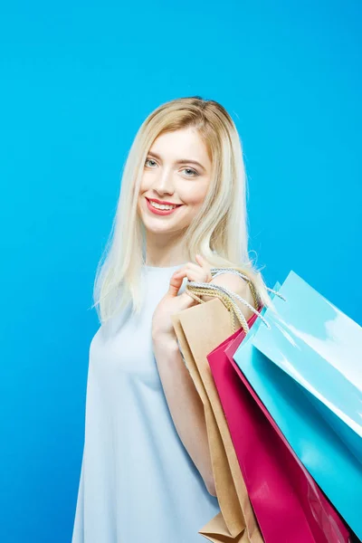 Портрет симпатичной блондинки с длинными волосами на синем фоне. Pretty Woman Holding a lot of Shopping Colorful Bags . — стоковое фото