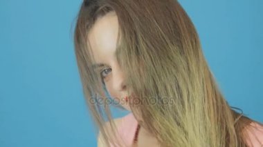 Uzun siyah saçları, pembe elbise ve çekici gülümseme Studio mavi zemin üzerine poz ile inanılmaz kadın.