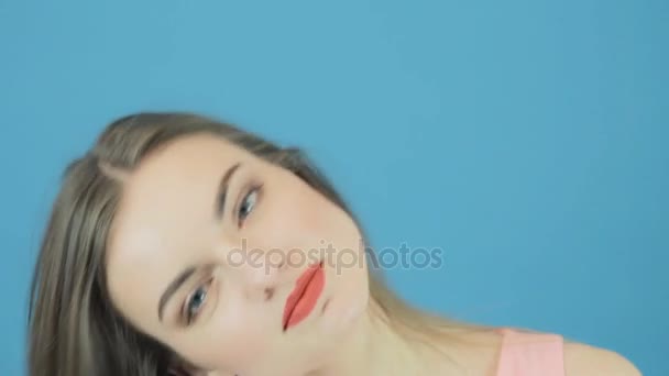 Closeup portret van mooie Brunette met lange haren, roze jurk en charmante glimlach poseren in Studio op blauwe achtergrond. — Stockvideo
