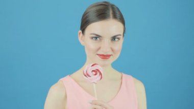 Mavi arka plan üzerinde elinde büyük tatlı lolipop mutlu güzel kızla. Mükemmel esmer şeker ile Studio poz.