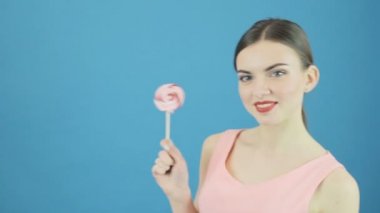 Mükemmel esmer şeker ile Studio poz. Büyük tatlı lolipop mavi arka plan üzerinde el ile mutlu güzel kız.