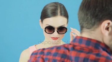 Esmer modeli sırasında Photoset. Erkek el bir şapka değişiyor. Kırmızı şapka ve pembe elbise şehvetli dudakları ile seksi kadın moda portre.