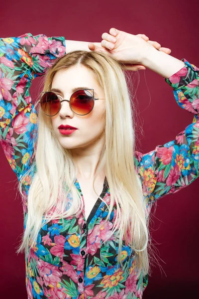 Портрет красивой модели крупным планом с солнцезащитными очками в красочной рубашке на розовом фоне. Cute Blonde позирует в студии . — стоковое фото