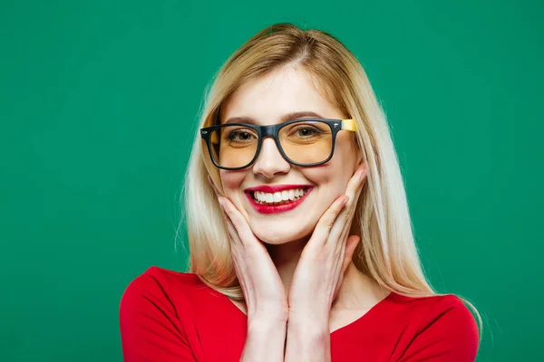 Primo piano Ritratto di Ragazza sorridente in Occhiali e Top rosso su sfondo verde. Giovane Bionda dai Capelli Lunghi e Sorriso di Charme in Studio . — Foto Stock