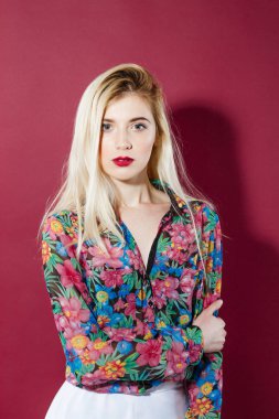 Şehvetli sarışın Model renkli gömlek uzun saçlı pembe arka plan kameraya bakıyor. Studio Posing harika dudakları ile güzel kız.