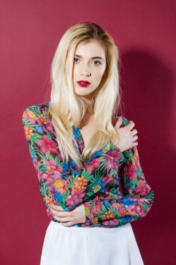 Harika sarışın Model renkli gömlek ve beyaz etek, pembe arka plan kameraya bakarak uzun saçlı portresi. Studio Posing şehvetli kızdır.