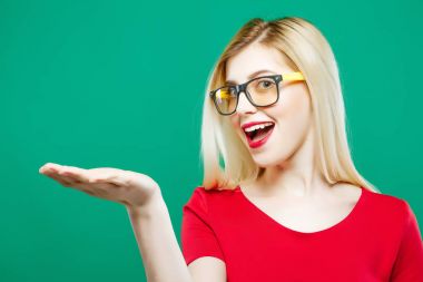 Uzun sarı saçları, gözlük ve Kırmızı Top elinde Studio yeşil arka plan üzerinde boş yer tutan sürpriz kadınla.