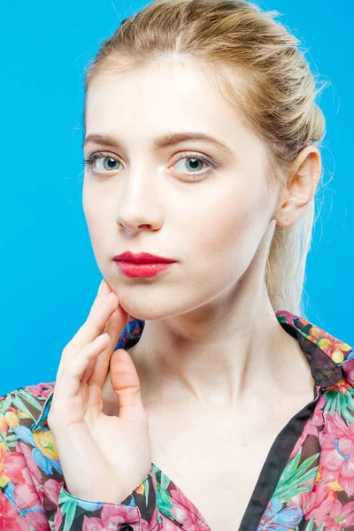 Linda chica con cola de caballo larga y labios sensuales con camisa de colores sobre fondo azul en el estudio. Concepto de cuidado de la piel . — Foto de Stock