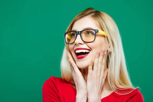 Ragazza ridente in Occhiali e Top rosso su sfondo verde. Primo Piano Ritratto di Giovane Bionda con Capelli Lunghi e Sorriso di Charme in Studio . — Foto Stock