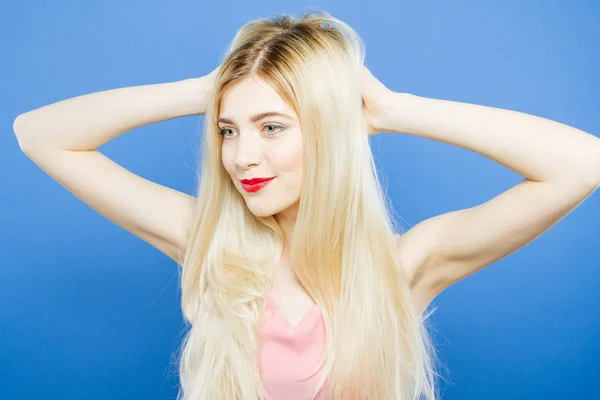 Ritratto di bionda carina con capelli lunghi e trucco professionale in studio su sfondo blu . — Foto Stock