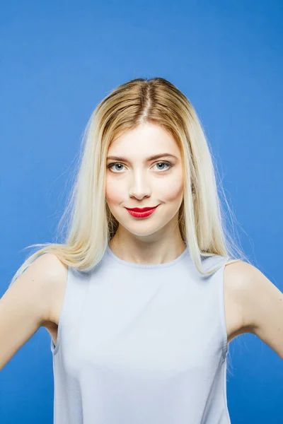 Front View of Amazing Pretty Woman with Long Hair Having Fun in Studio. Portrait of Smiling Blonde Wearing Elegant Dress on Blue Background. — Stock Photo, Image