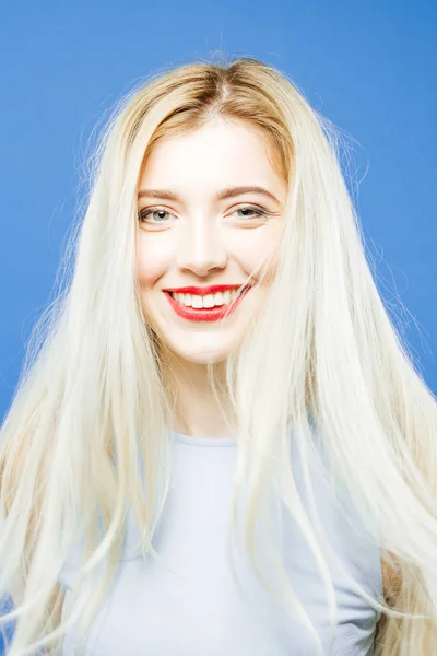 Woman with Toothy Smile on Blue Background. Portrait of Girl with Long Hair Wearing Elegant Dress and Having Fun in Studio. — Stock Photo, Image