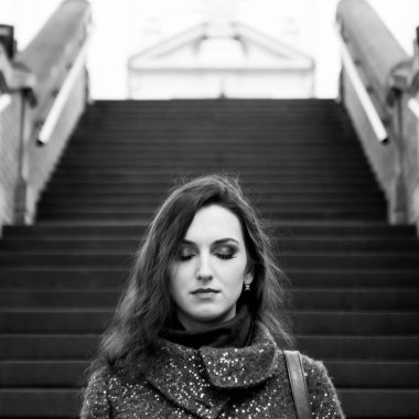 Çekici kadın kapalı gözler, uzun saçlı, şehvetli dudakları ve profesyonel makyaj sokakta duran. Siyah beyaz portre sevimli genç kadının açık havada. Arka merdivende.