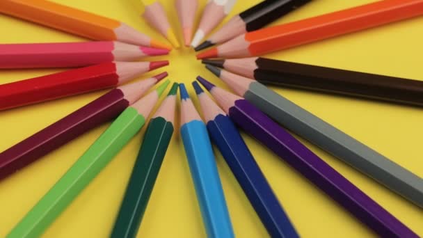 Crayons de couleur reposant sur un fond jaune vif dans un cercle . — Video