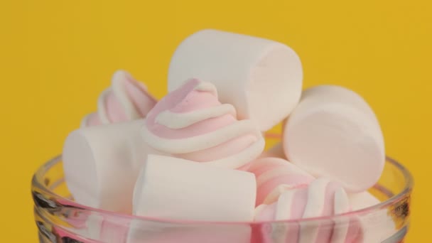 Marshmallow rosa retorcido y blanco en un tarro de vidrio sobre un fondo amarillo . — Vídeos de Stock