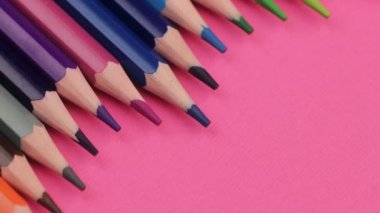 Birçok farklı renkli kalemler bir dalga pembe arka plan üzerinde yalan