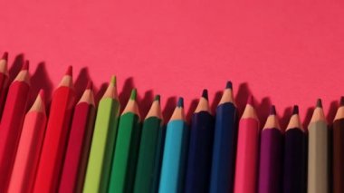 Birçok farklı renkli kalemler bir dalga pembe arka plan üzerinde yalan