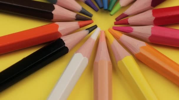 Lápis coloridos que jazem sobre fundo amarelo brilhante em um círculo . — Vídeo de Stock