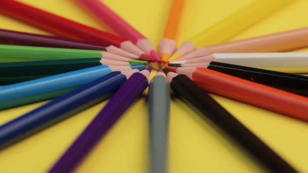 Lápices de colores acostados sobre un fondo amarillo brillante en un círculo . — Vídeos de Stock