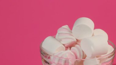 Pembe bir arka plan üzerinde bir cam kabın içinde farklı kabarık tatlı şekerleme.