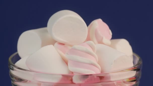 Ροζ στριμμένα και λευκό Marshmallow σε ένα γυάλινο βάζο σε μπλε φόντο. — Αρχείο Βίντεο
