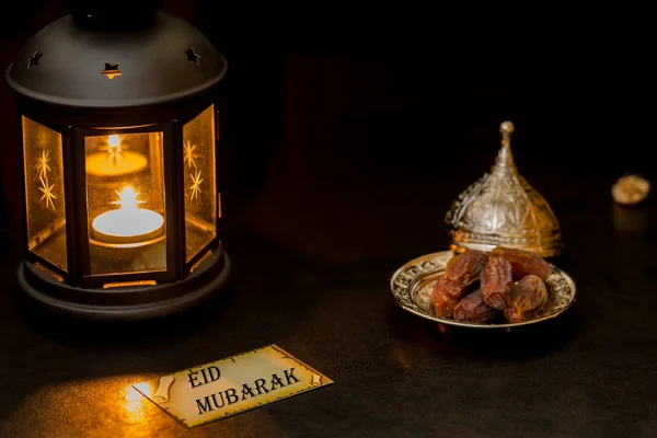 Tarjeta Eid mubarak con linterna y dátiles en la oscuridad — Foto de Stock