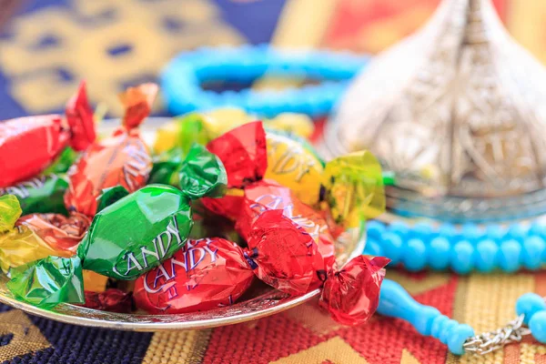 Dulces coloridos y rosario azul en la alfombra tradicional turca — Foto de Stock