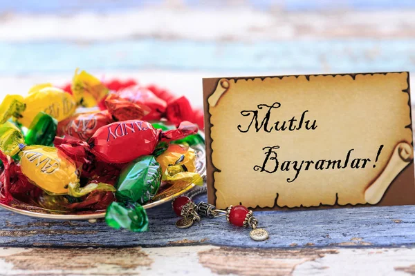 Eid mubarak en turco en la tarjeta con dulces de colores en la mesa — Foto de Stock