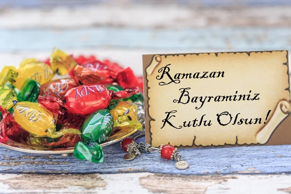 Feliz eid al fitr en turco en la tarjeta con caramelos en la mesa — Foto de Stock