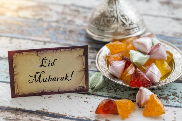 Eid mubarak texto en tarjeta de felicitación en mesa vintage con caramelos — Foto de Stock